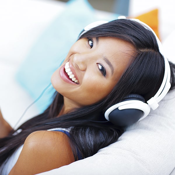 A woman in a pair of headphones is happily smiling