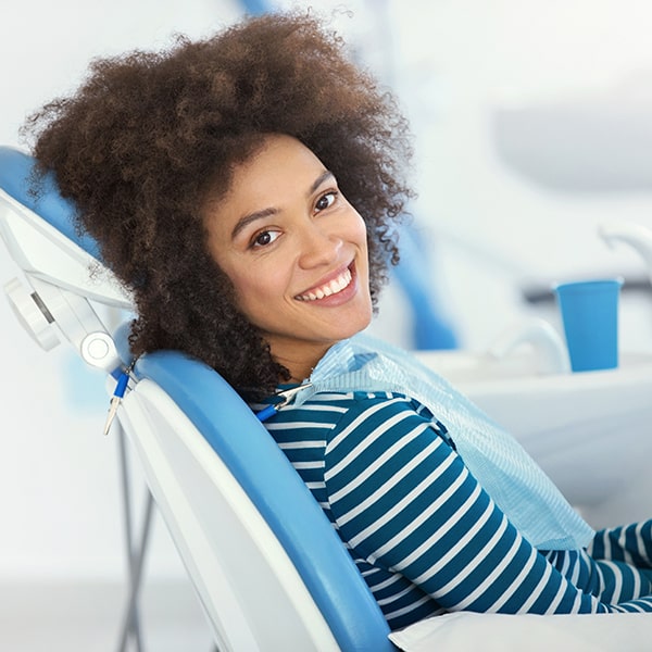 A woman with a curly hair happily smiling in a dental chair