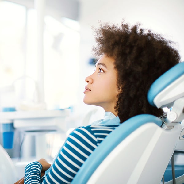 A woman with a curly hair in a dental chair at her emergency dentist appointment