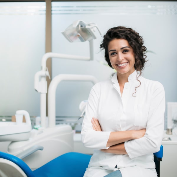 A dentist in her office is smiling 