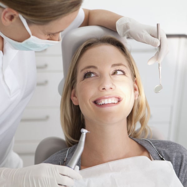 A woman in a dental chair is ready for a procedure and smiling