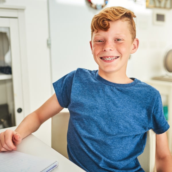 The red-haired boy smiles for braces and orthodontics