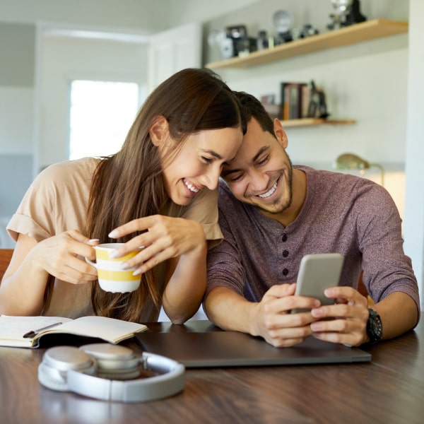 Happy couple smiling while looking at an iPhone